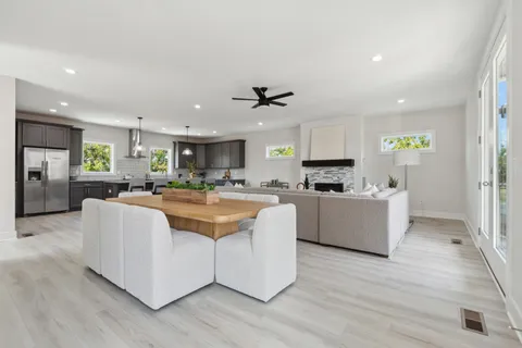 a large white kitchen with kitchen island a counter top space a sink stainless steel appliances and cabinets