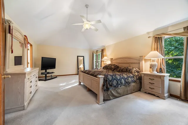 a spacious bedroom with a bed and a flat tv screen on dresser