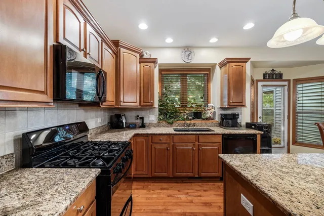 a kitchen with stainless steel appliances granite countertop wooden cabinets a stove top oven and granite counter tops