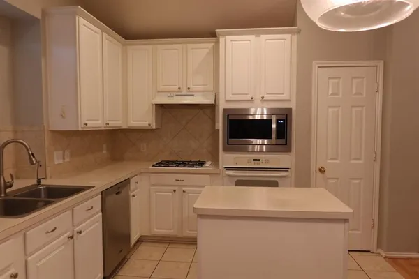 a kitchen with stainless steel appliances a sink a stove a refrigerator and cabinets