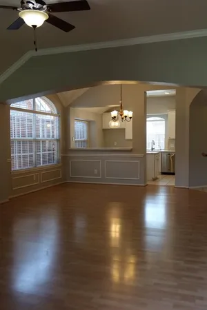 an empty room with wooden floor chandelier and windows