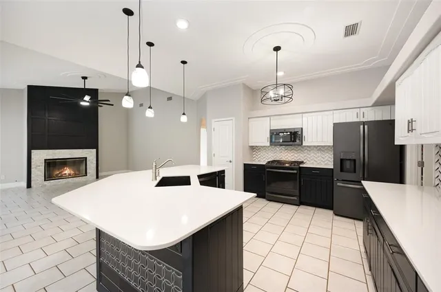 a kitchen with stainless steel appliances a stove a refrigerator a sink and a fireplace