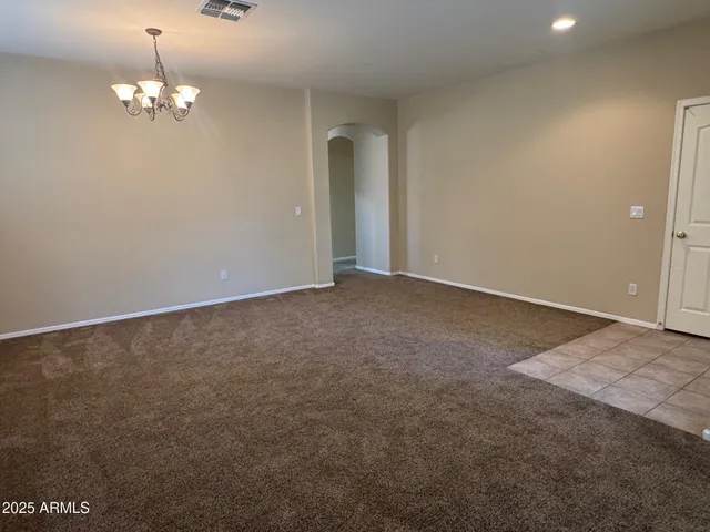 a view of an empty room with a chandelier fan