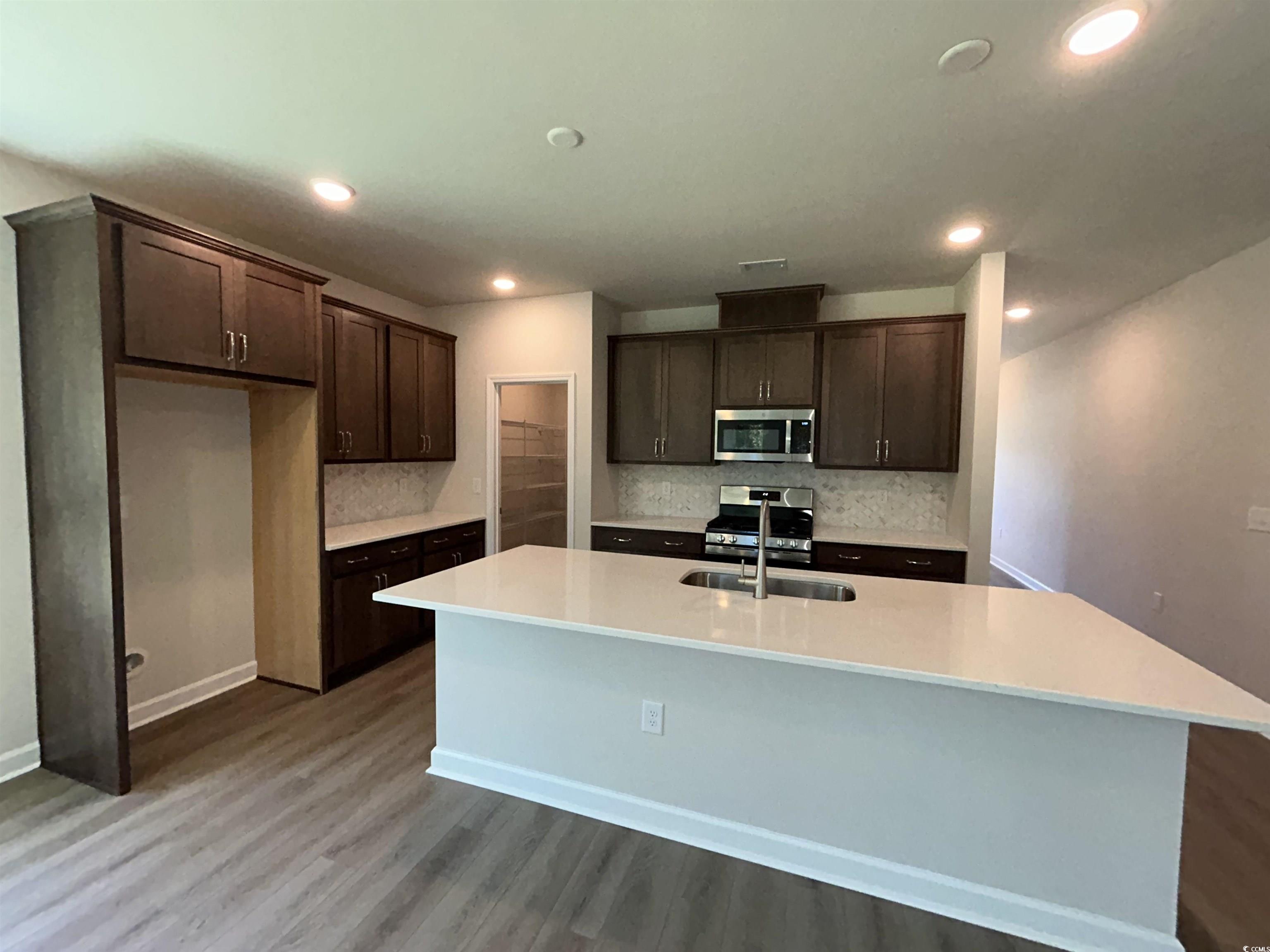 3068 Palma Way Myrtle Beach, SC 29579 - Photo 16 of 30 Kitchen featuring stainless steel appliances, decorative backsplash, dark brown cabinetry, a center island with sink, and recessed lighting