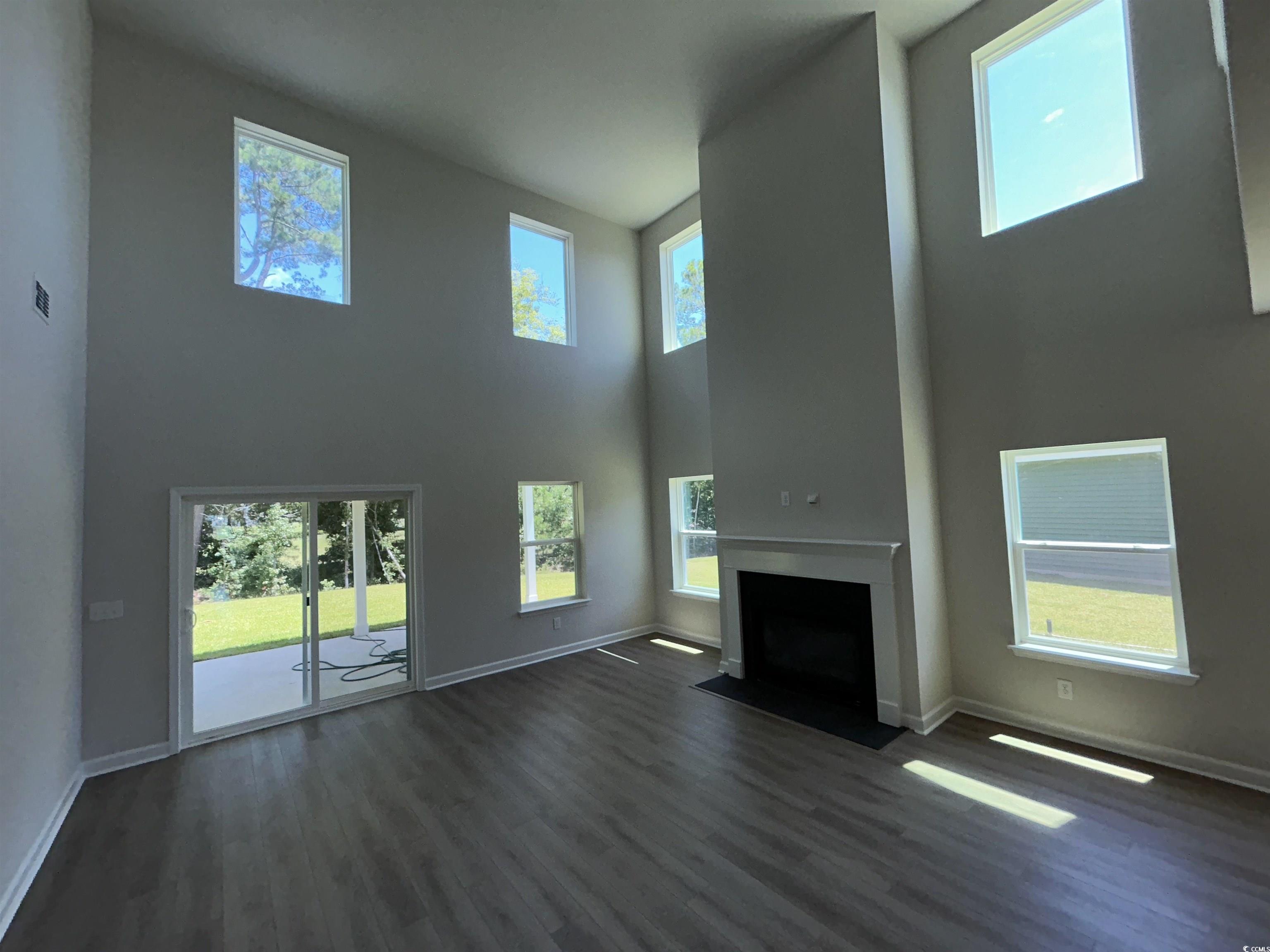 3068 Palma Way Myrtle Beach, SC 29579 - Photo 18 of 30 Unfurnished living room with a towering ceiling, a fireplace with flush hearth, dark wood-style floors, and healthy amount of natural light