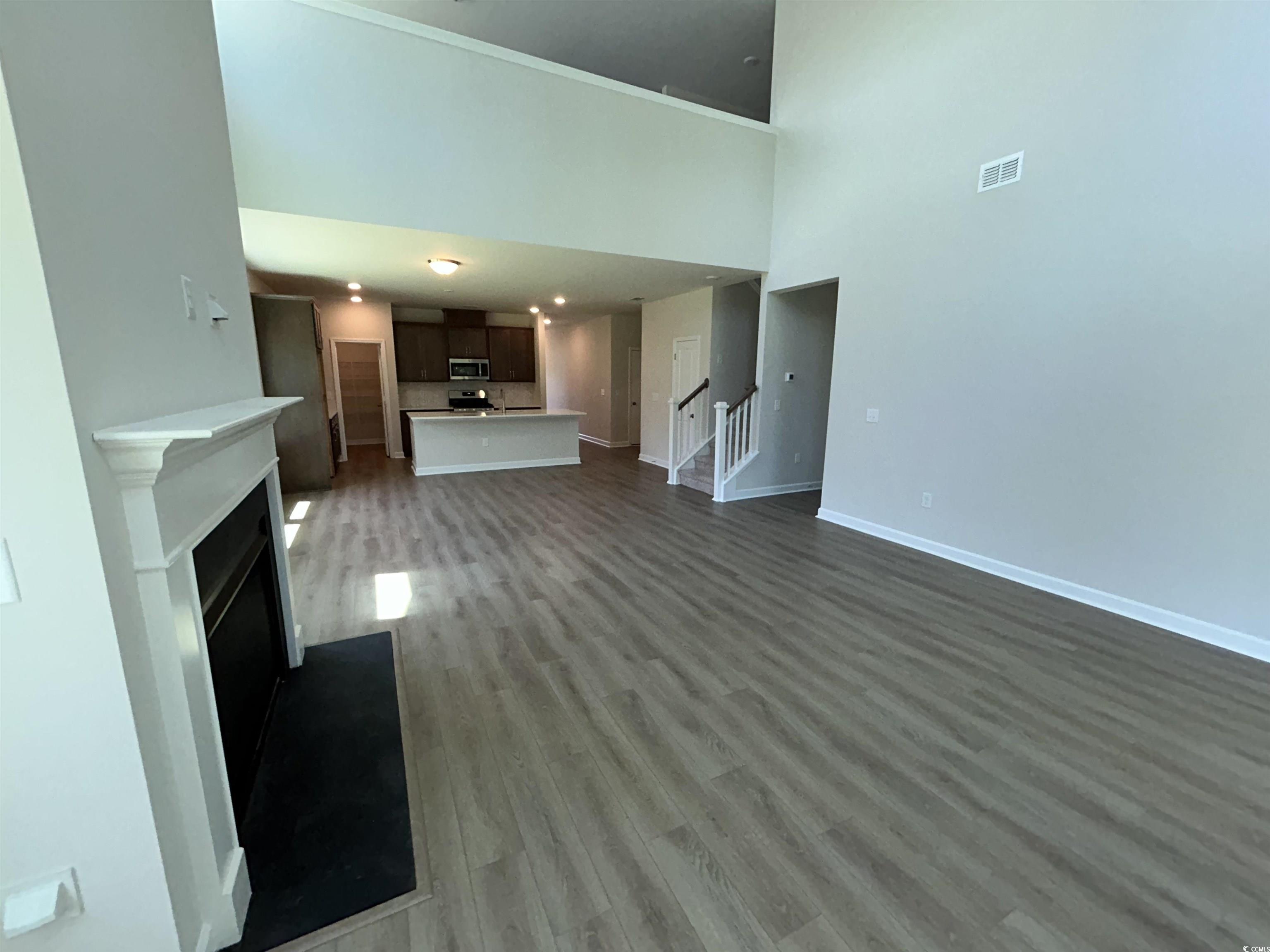 3068 Palma Way Myrtle Beach, SC 29579 - Photo 19 of 30 Unfurnished living room with wood finished floors, stairs, a fireplace, and a high ceiling