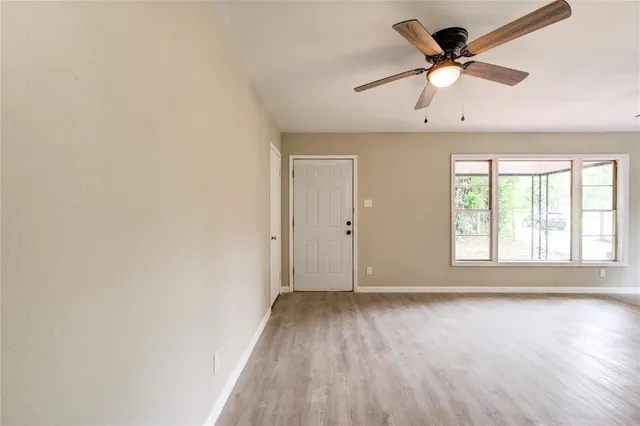 a view of an empty room with window and wooden floor