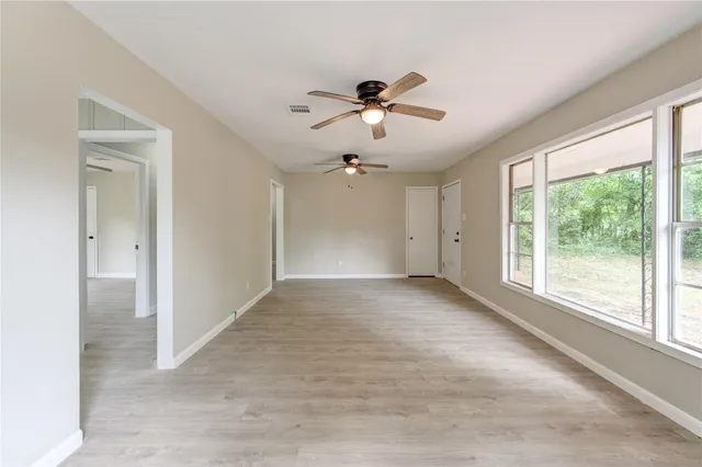 a view of empty room with wooden floor and ceiling fan
