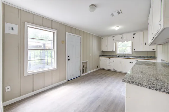 a large kitchen with cabinets wooden floor and stainless steel appliances
