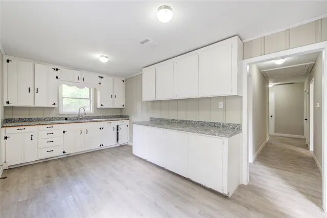 a kitchen with granite countertop white cabinets and sink