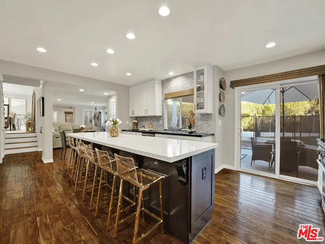 a kitchen with stainless steel appliances granite countertop a kitchen island a stove a refrigerator a sink and a dining table with wooden floor
