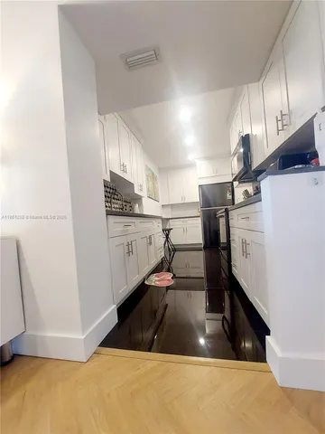 a kitchen with stainless steel appliances a sink a stove a microwave a refrigerator a counter space and cabinets