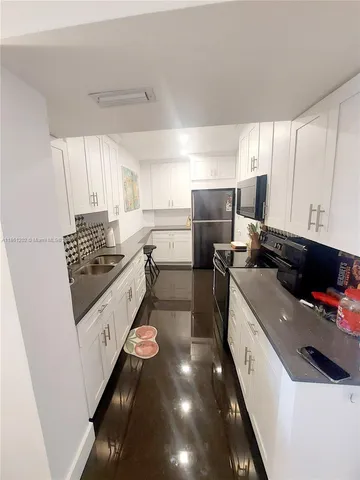 a kitchen with a sink a counter top space appliances and cabinets