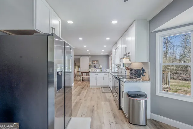 a kitchen with stainless steel appliances granite countertop a refrigerator and a wooden floors