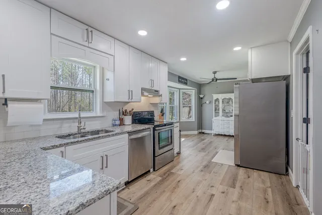 a kitchen with granite countertop a sink stainless steel appliances and window