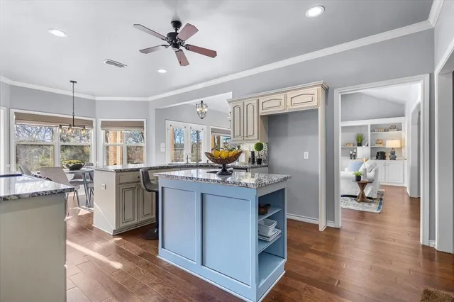 a living room with granite countertop kitchen island stainless steel appliances furniture a fireplace and a chandelier