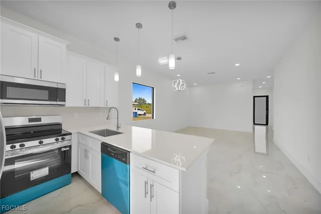 a kitchen with a sink a counter top space stainless steel appliances and cabinets
