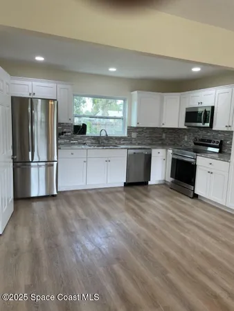 a kitchen with stainless steel appliances granite countertop a refrigerator stove top oven and sink