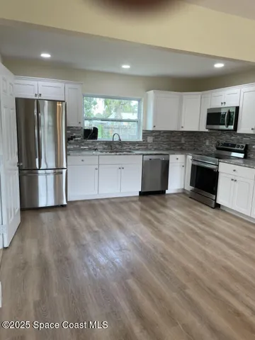 a large kitchen with cabinets wooden floor and stainless steel appliances