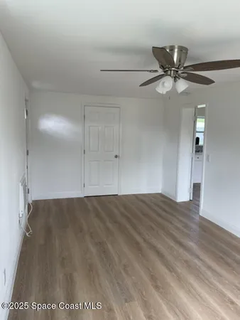 a view of an empty room and window with a ceiling fan