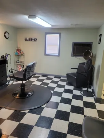 a living room with a black white checkered floor with a gaming machine and dining chairs