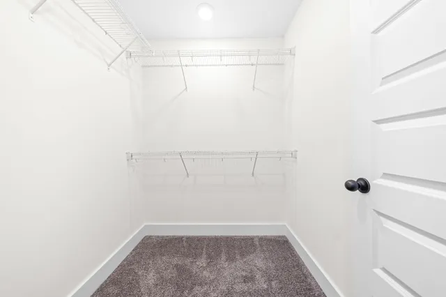 an empty room with chandelier fan and windows