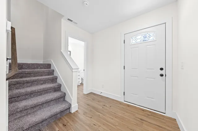an empty room with wooden floor fireplace and windows