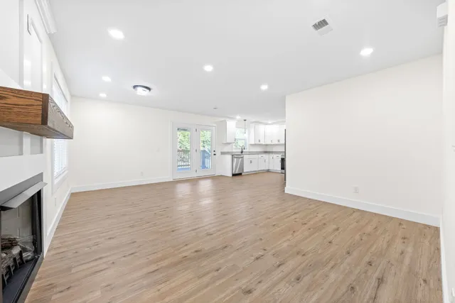 an empty room with wooden floor a fireplace and windows