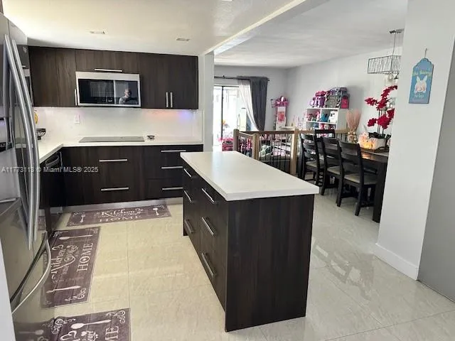 a kitchen with stainless steel appliances kitchen island granite countertop a sink and a refrigerator