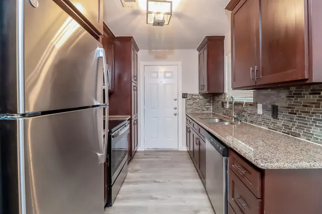 a kitchen with stainless steel appliances granite countertop a refrigerator a stove and a sink