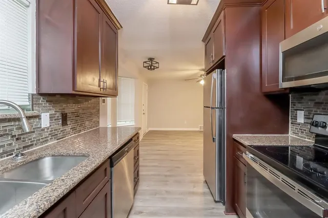a kitchen with granite countertop a sink stove and refrigerator