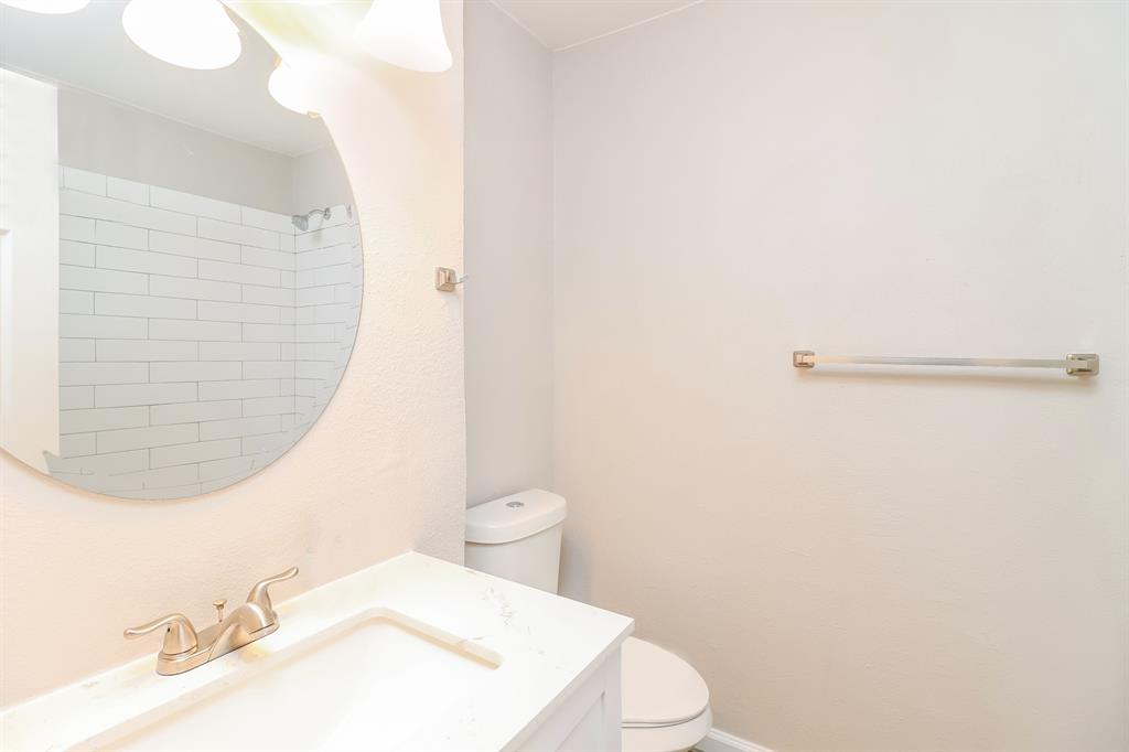 4117 Hatcher Street Fort Worth, TX 76119 - Photo 10 of 16 a white toilet sitting next to a bathroom sink and a mirror