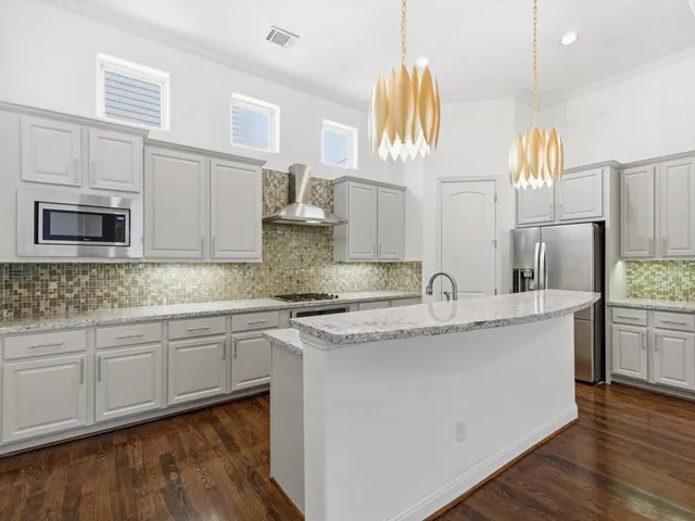 a kitchen with stainless steel appliances granite countertop a sink a stove and a wooden cabinets