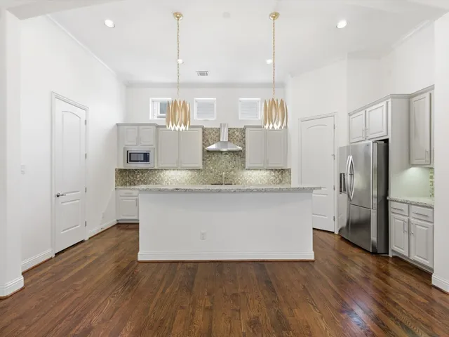 a view of kitchen with granite countertop stainless steel appliances and wooden floor