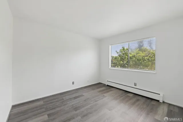 an empty room with wooden floor and window