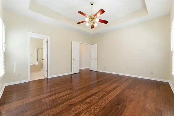 an empty room with wooden floor and a ceiling fan