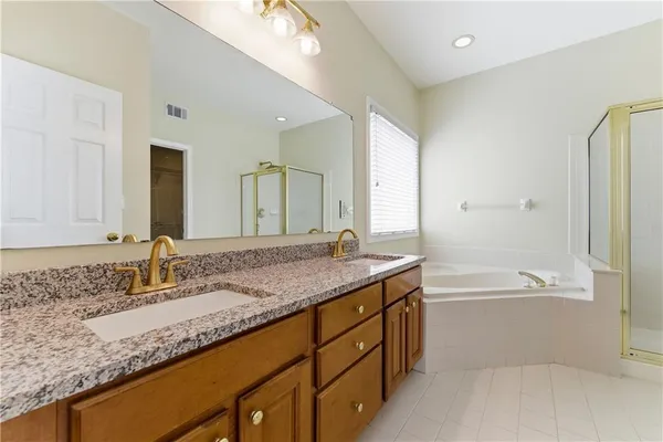 a bathroom with a granite countertop bathtub a sink and a mirror