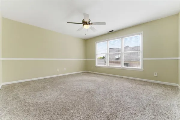 an empty room with windows and fan