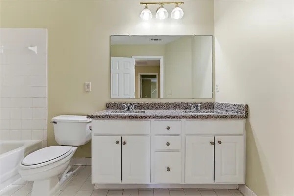a bathroom with a granite countertop toilet sink and mirror