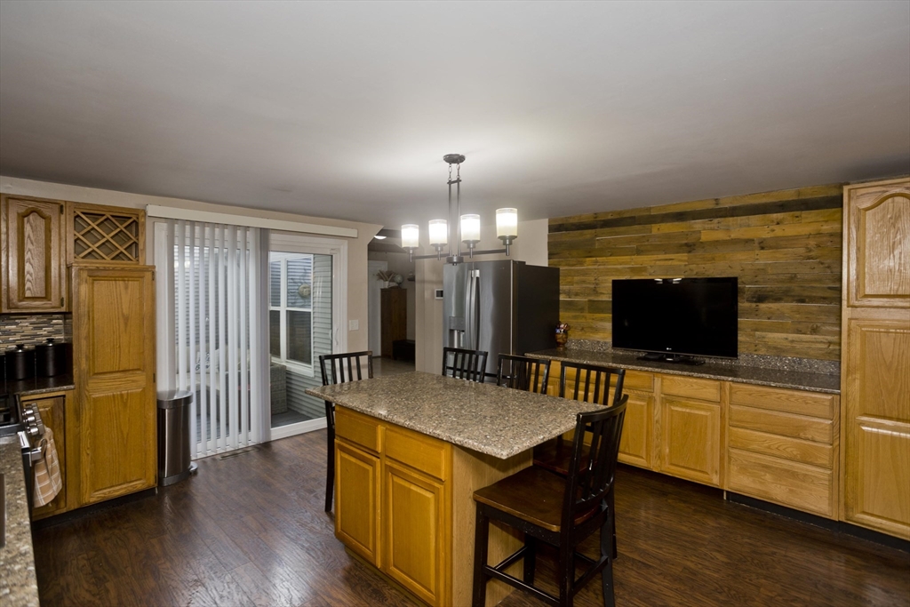 391 Plumtree Road Springfield, MA 01118 - Photo 12 of 42 a living room with stainless steel appliances kitchen island granite countertop wooden floor a couch and a flat screen tv