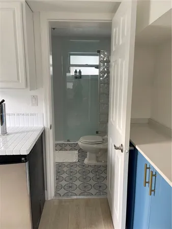 a bathroom with a granite countertop sink a toilet a shower and a mirror