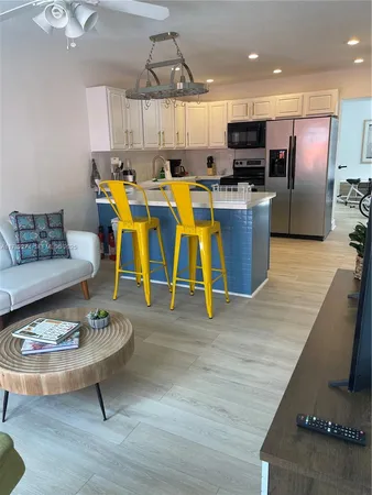 a living room with stainless steel appliances furniture and a kitchen view