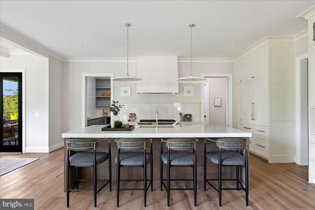 a dining room with wooden floor a chandelier a glass table and chairs