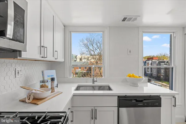 a kitchen with stainless steel appliances a sink a stove and a refrigerator with wooden floor