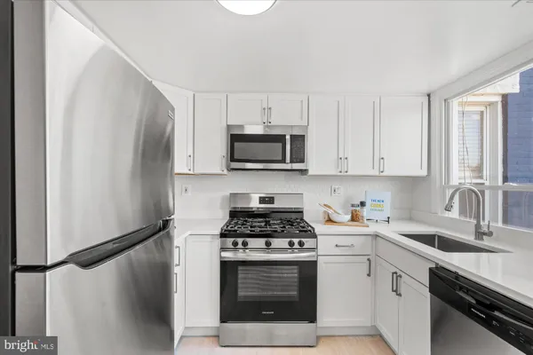 a kitchen with white cabinets and stainless steel appliances