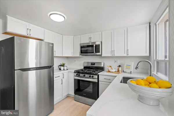 a kitchen with stainless steel appliances a refrigerator sink and white cabinets