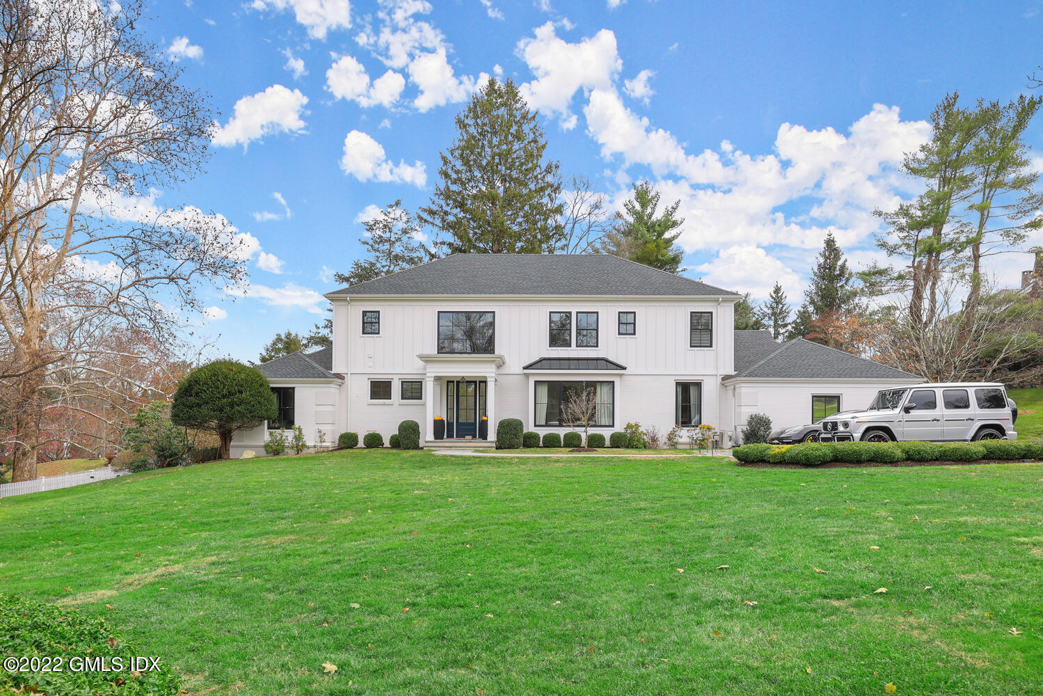 a front view of a house with garden and trees