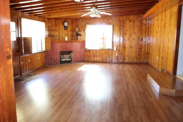 a view of a room with wooden floor fireplace and windows