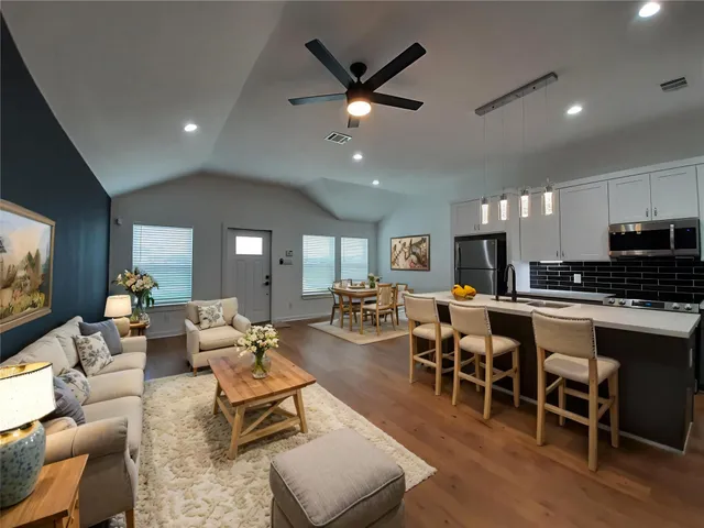 a living room with furniture kitchen view and a flat screen tv