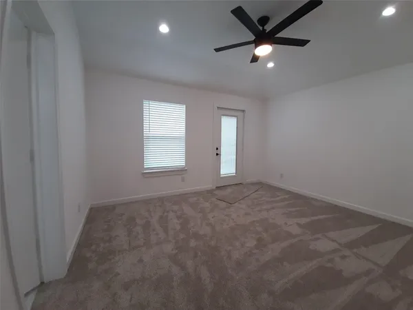an empty room with windows and a ceiling fan